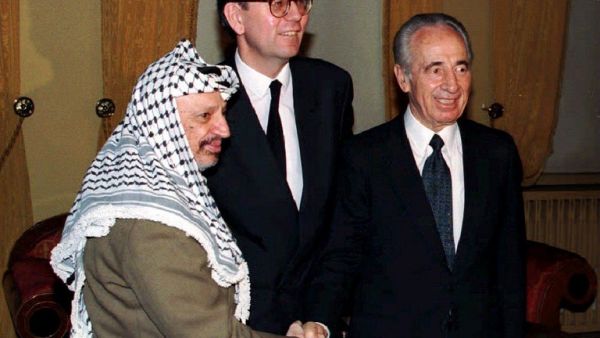 This file photo taken on January 22, 1994 shows Israeli Foreign Minister Shimon Peres (R) and PLO Chairman Yasser Arafat (L) shaking hands as they pose with the new Norwegian Foreign Minister Bjoern Tore Godal in Oslo. (AFP/Stringer)