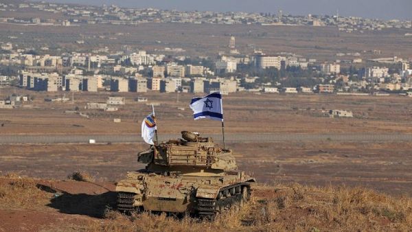 An Israeli flag flutters above the wreckage of a tank on a hill in the Golan Heights overlooking the border with Syria on October 18, 2017. (AFP Photo/Jalaa Marey)