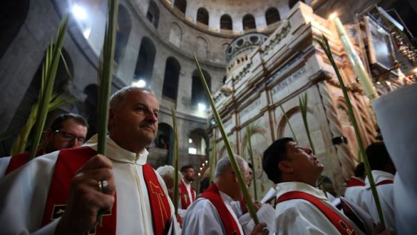 Catholic priests hold palm branches as they circle the aedicule during the Palm Sunday Easter procession at the Church of the Holy Sepulchre in Jerusalem's Old City on April 9, 2017. (AFP/Gali Tibbon)