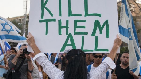 An Israeli woman holds up a sign with 'Too many terrorists in prison' on one side and 'Kill them all!' on the other - in reference to Palestinians. (AFP/File)