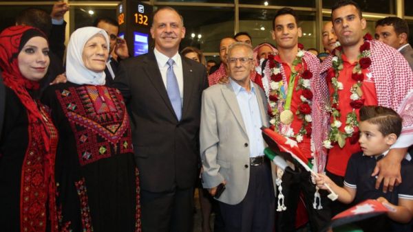 Jordanian Prince Faisal bin al-Hussein (3L) poses for a photo with Ahmed Abughaush (3R) who won the men's 68-kg taekwondo competition at the Olympics in Rio de Janeiro during a welcome ceremony upon his arrival at the Queen Alia International Airport in Amman on August 23, 2016. (AFP/Khalil Mazraawi)