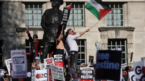 Pro-Palestine demonstrators hold placards and wave flags during a protest opposite the entrance to Downing Street in central London /AFP