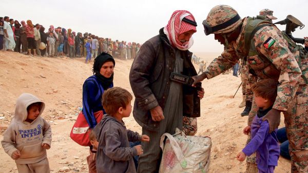 A Jordanian soldier scans newly arrived Syrian refugees as they wait to cross the border. (AFP/ File Photo)