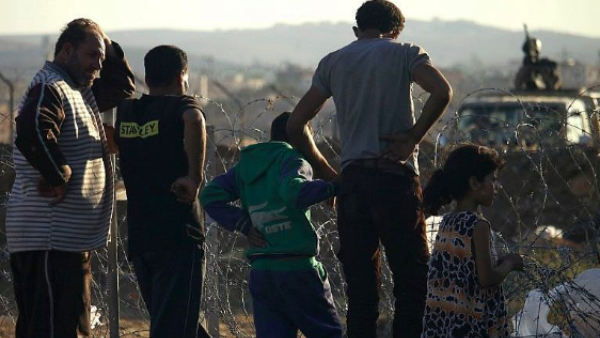A Jordanian army soldier stands on a jeep behind barbed wire as displaced Syrians from Daraa fleeing shelling by pro-government forces  in a makeshift camp, near the town of Nasib, southern Syria, July 2, 2018. (AFP Photo/Mohamad Abazeed)
