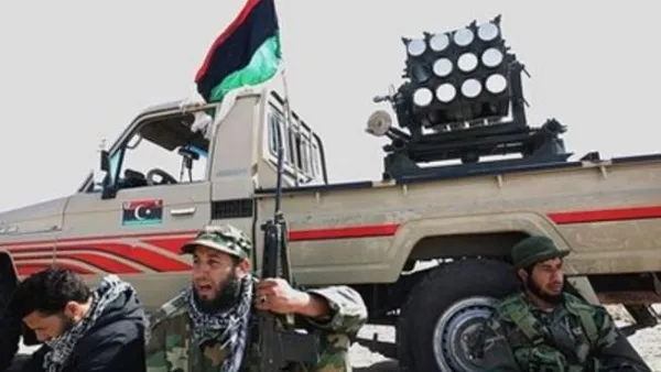 ثوار ليبيون يجلسون عند سيارة محملة بقاذفة صواريخ قرب اجدابيا