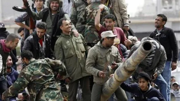 الثوار الليبيون فوق دبابة اسروها من القوات الموالية للزعيم الليبي معمر القذافي في بنغازي
