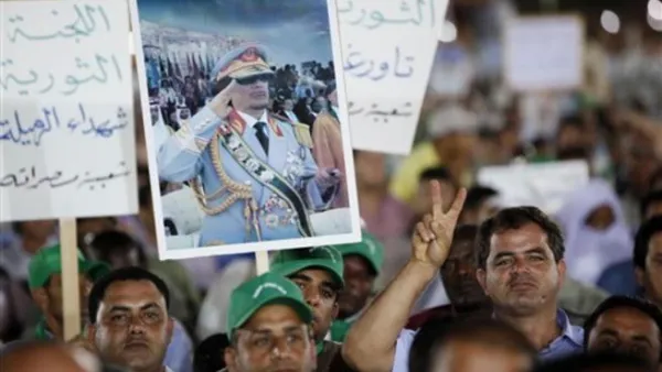القذافي يوزع السلاح على الليبيين