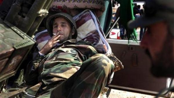 مقاتل معارض للزعيم الليبي معمر القذافي يدخن على خط الجبهة بين بن جواد وراس لانوف
