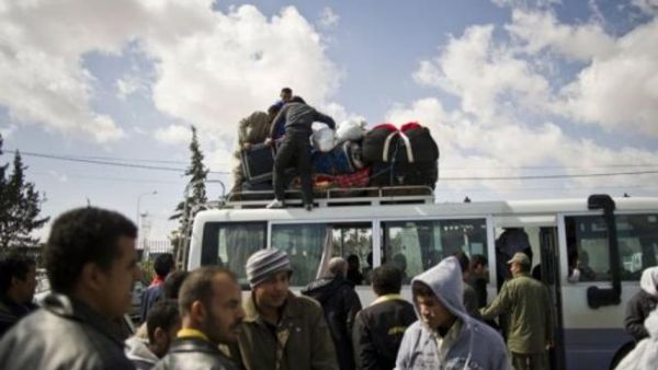 مجموعة من الرجال الذين غادروا ليبيا ينتظرون عند معبر راس جدير الحدودي قرب مدينة بن قردان التونسية
