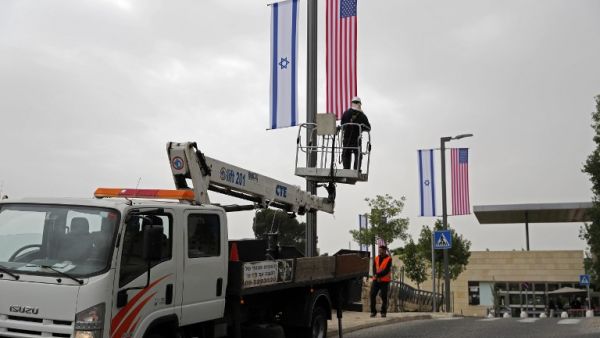 A worker installs decorations of Israeli and US flags in front of the US Consulate in Jerusalem where US officials will install the new US Embassy/ AFP