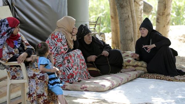 Syrian refugee women sit on mats talking at an unofficial camp for refugees in the village of Bar Elias in the Bekaa Valley in central Lebanon (AFP/ JOSEPH EID)