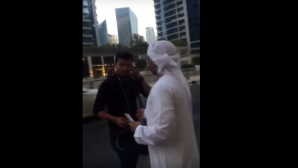 Screenshot from the video showing two men in Emirati traditional attire while handing random people in the street cash money.