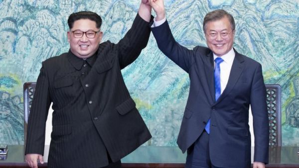 North Korea's leader Kim Jong Un (L) and South Korea's President Moon Jae-in (R) raise their joined hands during a signing ceremony near the end of their historic summit. (AFP/ File Photo)
