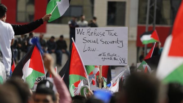 Palestinians wave national flags as they take part in a protest against a social security law proposed by the Palestinian Authority in the West Bank city of Ramallah on November 12, 2018. (ABBAS MOMANI / AFP)
