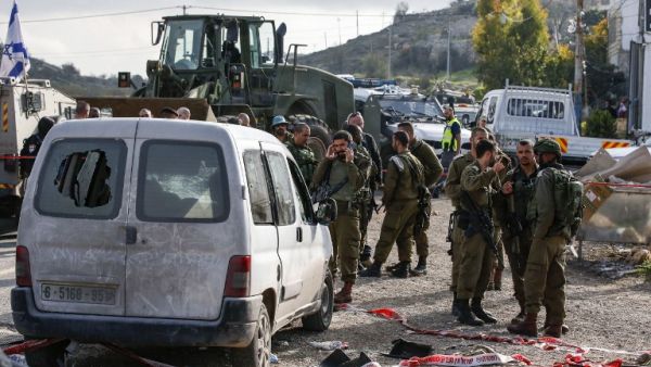 This picture taken on November 26, 2018 shows Israeli soldiers standing by a damaged car at the scene of an attack where a Palestinian man rammed a vehicle into three Israeli soldiers. (AFP/File)