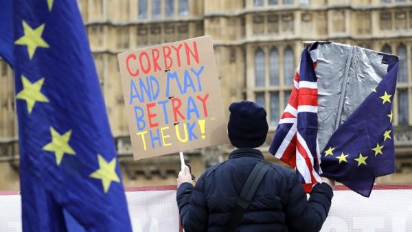 An anti-Brexit activist holds a placard and Union and EU flags as they demonstrate outside the Houses of Parliament in London on March 27, 2019. (Tolga AKMEN/ AFP)