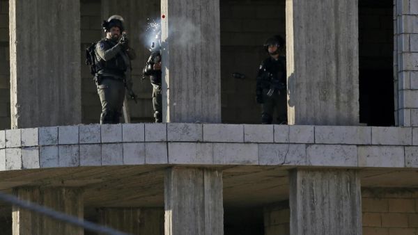 An Israeli soldier fires a tear gas canister at Palestinian stone throwers following a raid in the West Bank city of Ramallah, 10th of December. (AFP)