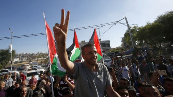 Mohammed al-Qiq flashes a peace sign as he arrives back to his village in the West Bank. (AFP/Hazem Bader)