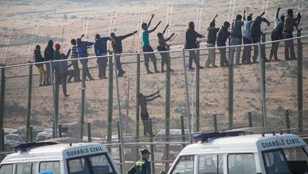 Would-be immigrants stand atop a border fence separating Morocco from the Spanish enclave of Melilla on May 1, 2014, following a morning assault on the border in an attempt to cross into Spain. (AFP/File)