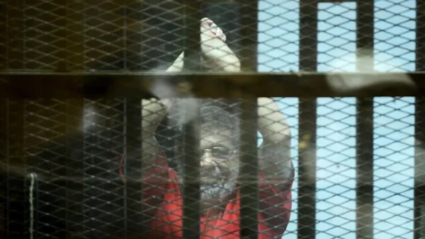 This file photo taken on June 18, 2016 shows Egypt's ousted Islamist president Mohamed Morsi, wearing a red uniform, gesturing from behind the defendant's bars during his trial on espionage charges at a court in Cairo. (AFP FILE)