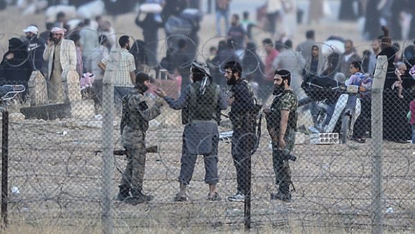 Men, believed to be Daesh militants, speak as people carry belongings back to Tal Abyad. (AFP/File)