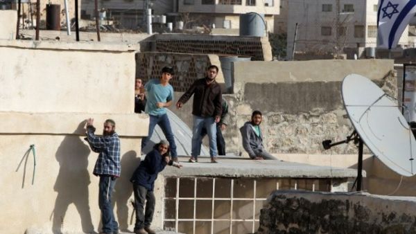 Jewish settlers stand on the roof of a building after entering two homes in the center of Hebron on January 21, 2016. (AFP/Hazem Bader)