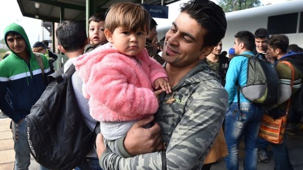 A Syrian man holds his child as he gets off the train in Munich, Germany. (AFP/File)