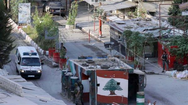 Members of the Palestinian Fatah movement and Lebanese army soldiers watch as an ambulance evacuates the wounded from Ain al-Hilweh refugee camp. (AFP/File)