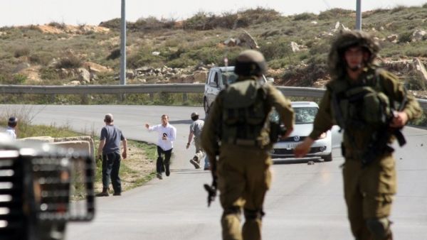 Israeli soldiers are seen close to settlers who appear to attack a photographer's car. (AFP/File)