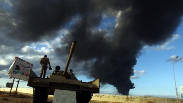 A member of the Libyan army stands on a tank as heavy black smoke rises from the city's port during clashes against Islamist gunmen in the eastern Libyan city of Benghazi on December 23, 2014. (AFP/Abdullah Doma)