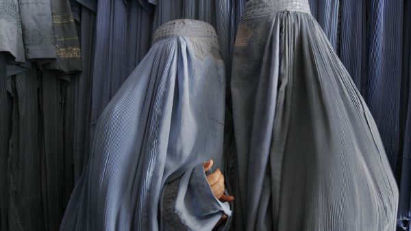 Two Afghan women clad in burqas whisper in a shop in Kabul, 2007. (AFP/File)