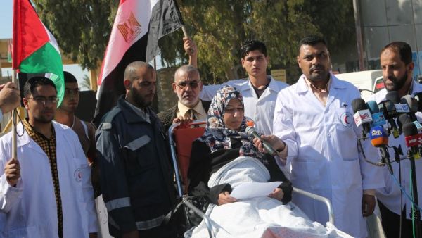 Palestinian medical staff stand next to a patient as she speaks to the media, calling on Egypt to open the Rafah crossing in the southern Gaza Strip on November 6, 2014. (AFP/Said Khatib)