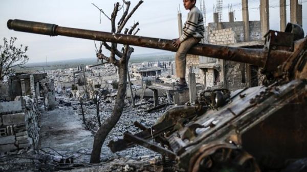 A Syrian Kurdish boy sits on a destroyed tank in the Syrian town of Kobane, also known as Ain al-Arab, on March 27, 2015. (AFP/Yasin Akgul)