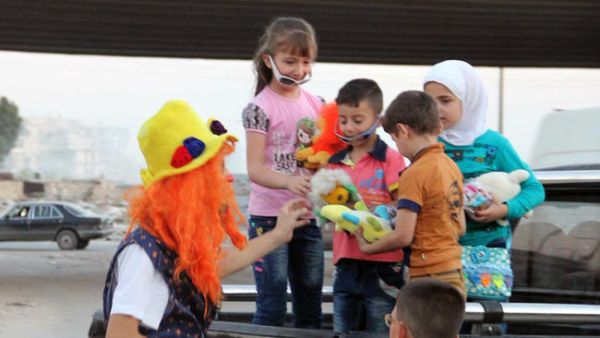 This undated photo courtesy of Ahmad al-Khatib, a media activist in Aleppo, shows Syrian social worker Anas al-Basha, 24, dressed as a clown, distributing toys to children in Aleppo, Syria. (Twitter)