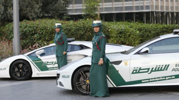 Emirati female police officers pose in front of Lamborghini (L) and Ferrari police vehicles. (AFP/File)