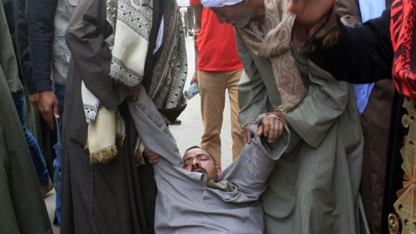 A relative of a supporter of Egyptian ousted Islamist president Mohamed Morsi is supported as he faints outside the courthouse on March 24, 2014 in the central Egyptian city of Minya, after the court ordered the execution of 529 Morsi supporters after only two hearings. (AFP/File)