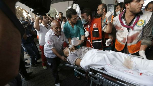 Palestinian paramedics carry a man wounded in a strike at a marketplace in the Shejaiya neighborhood. (AFP/File)
