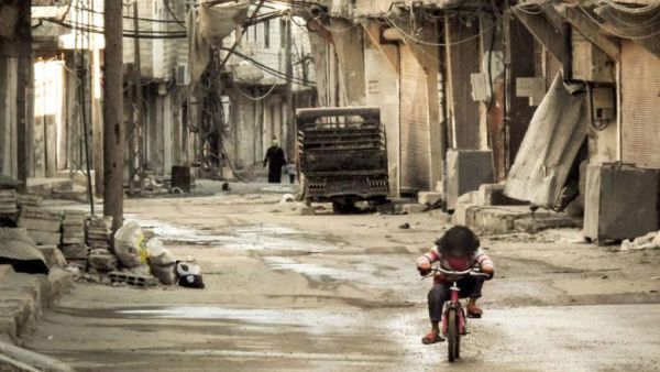 A Syrian girl rides her bicycle in an almost deserted street in the Teshrin neighborhood of the Qabun area in Damascus on 3 January 2013. (AFP/Omar Al-Khani)