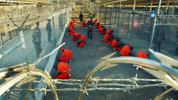 Al-Qaeda and Taliban detainees sit in a holding area under the surveillance of U.S. Military police at Camp X-Ray, a temporary prison site at Guantanamo Bay. (AFP/File)