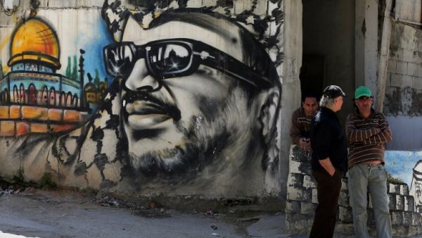 Palestinian refugees stand next to graffiti bearing a portrait of late Palestinian President Yasser Arafat at the Ain Al-Helweh refugee camp. (AFP/File)