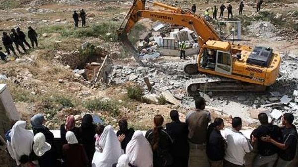 Palestinians watch an Israeli excavator destroying a Palestinian house in a village in the West Bank. (AFP/File)