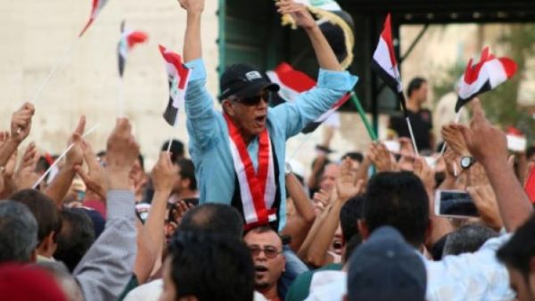 An Iraqi man chants slogans as other wave their national flag during a demonstration against corruption. (AFP/File)