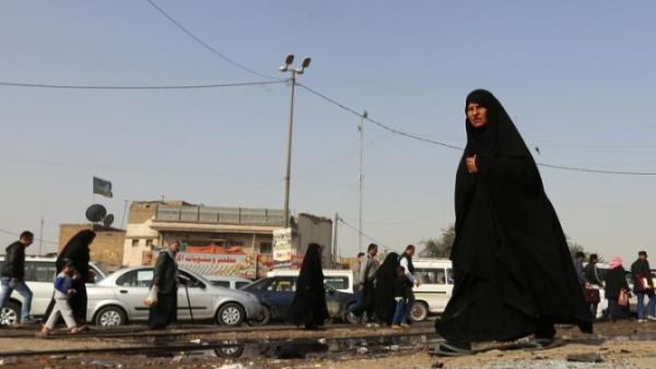 An Iraqi woman walks past a pool of blood on the aftermath of a suicide bomb. (AFP/File)