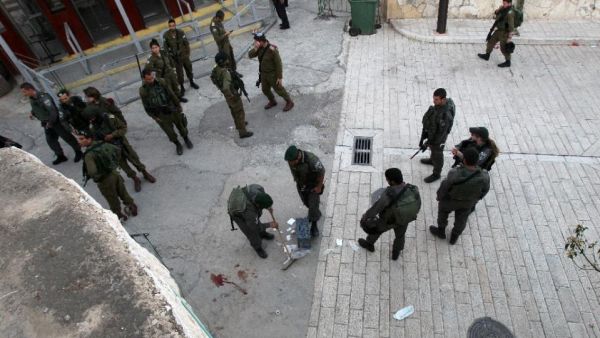 Israeli security forces clean the pavement at the site where a Palestinian was shot dead after stabbing a border policeman on April 25 2015 near the Tomb of the Patriarchs. (AFP/File)