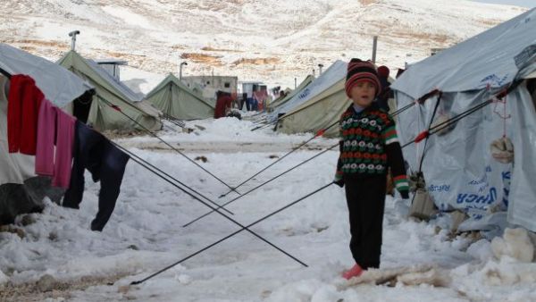 A Syrian child stands in the snow in a refugee camp in the town of Arsal in the Lebanese Bekaa valley on December 13, 2013. (AFP/File)