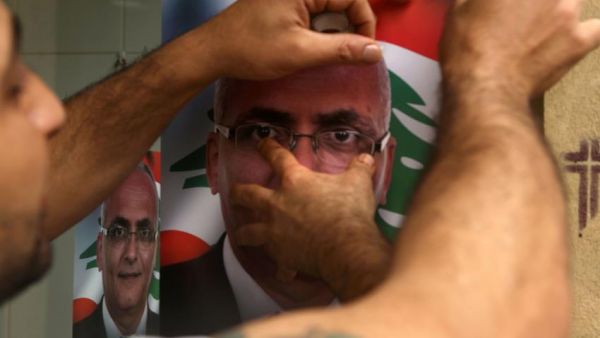 A Lebanese man puts up a poster of a candidate for the upcoming elections. (AFP/File)