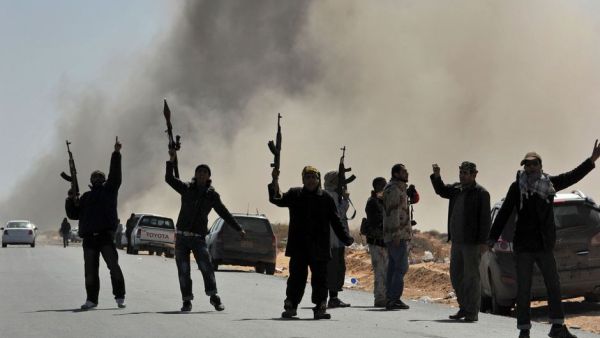 Libyan rebel fighters defiantly raise their weapons after a bomb dropped by an airforce fighter jet explodes. (AFP/Roberto Schmidt)