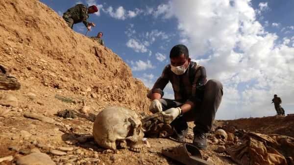 An Iraqi man inspects the remains of members of the Yazidi minority killed by the Daesh jihadist group, February 3, 2015. (AFP/Safin Hamed)