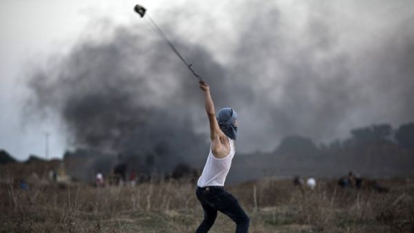 A Palestinian protester uses a slingshot to throw stones towards Israeli soldiers during clashes. (AFP/File)