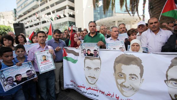 Palestinians hold banners in support of borther Muhammad and Mahmoud al-Balboul, and Malik al-Qadi, in the West Bank city of Nablus, on 21 September. (AFP/File)